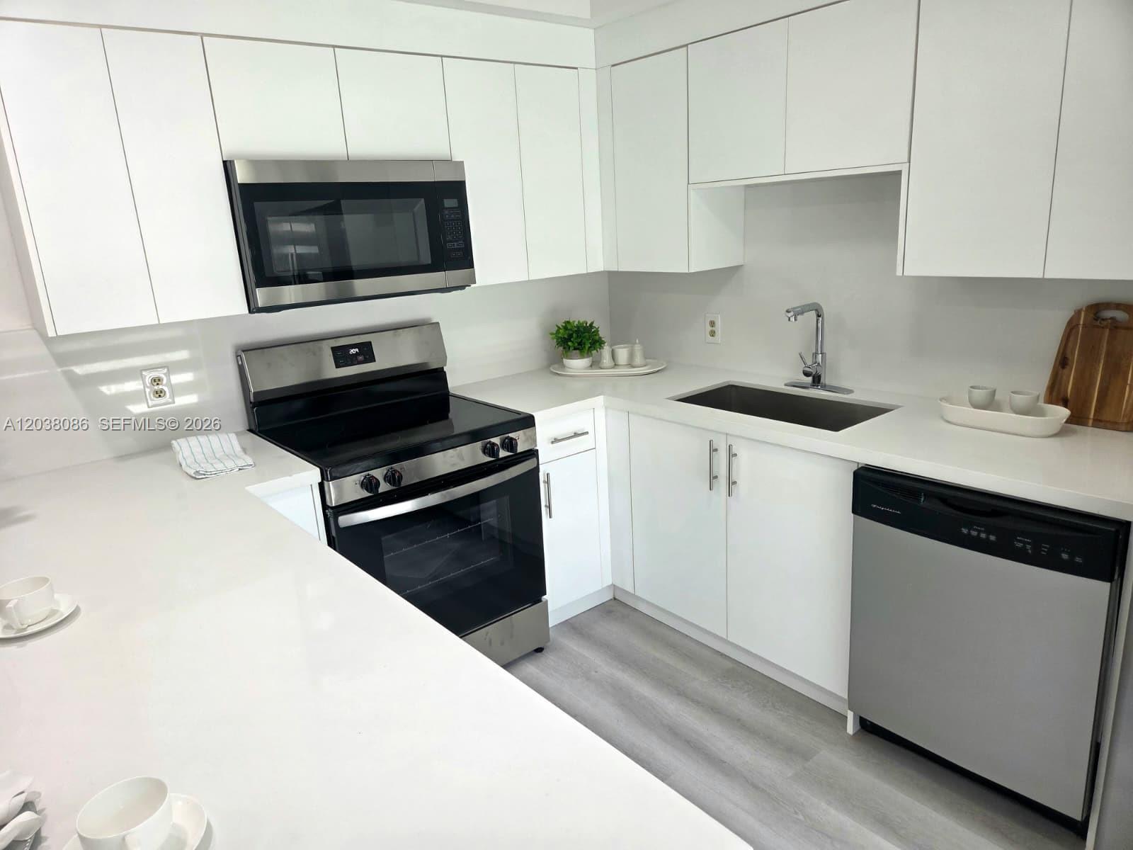 A modern kitchen features white cabinets, stainless steel appliances, and white quartz countertops — 2565 Garden Ct, Cooper City FL 33026, COOPER CITY, FL