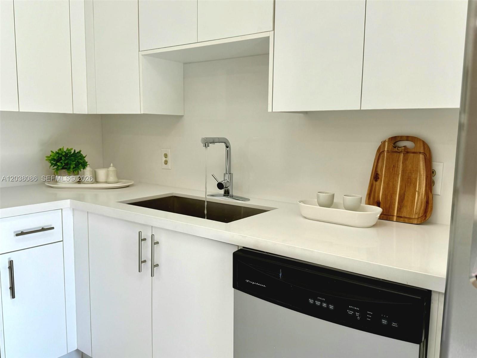 A modern kitchen features white cabinets, a stainless steel sink, and a black dishwasher — 2565 Garden Ct, Cooper City FL 33026, COOPER CITY, FL
