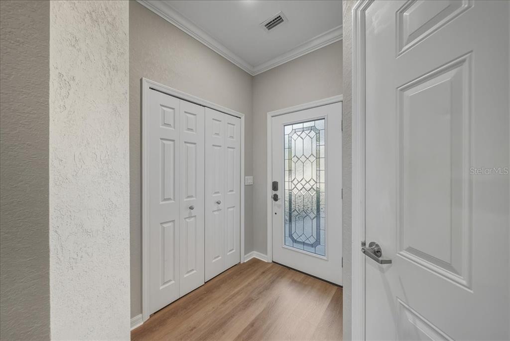 An entryway features wood-look flooring, a white front door with glass, and a bi-fold closet — 7224 KETCH PLACE, BRADENTON, FL