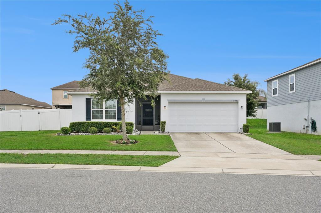 A single-story house with a white exterior, a two-car garage, and a front yard tree — 15280 WHITE TAIL LOOP, MASCOTTE, FL