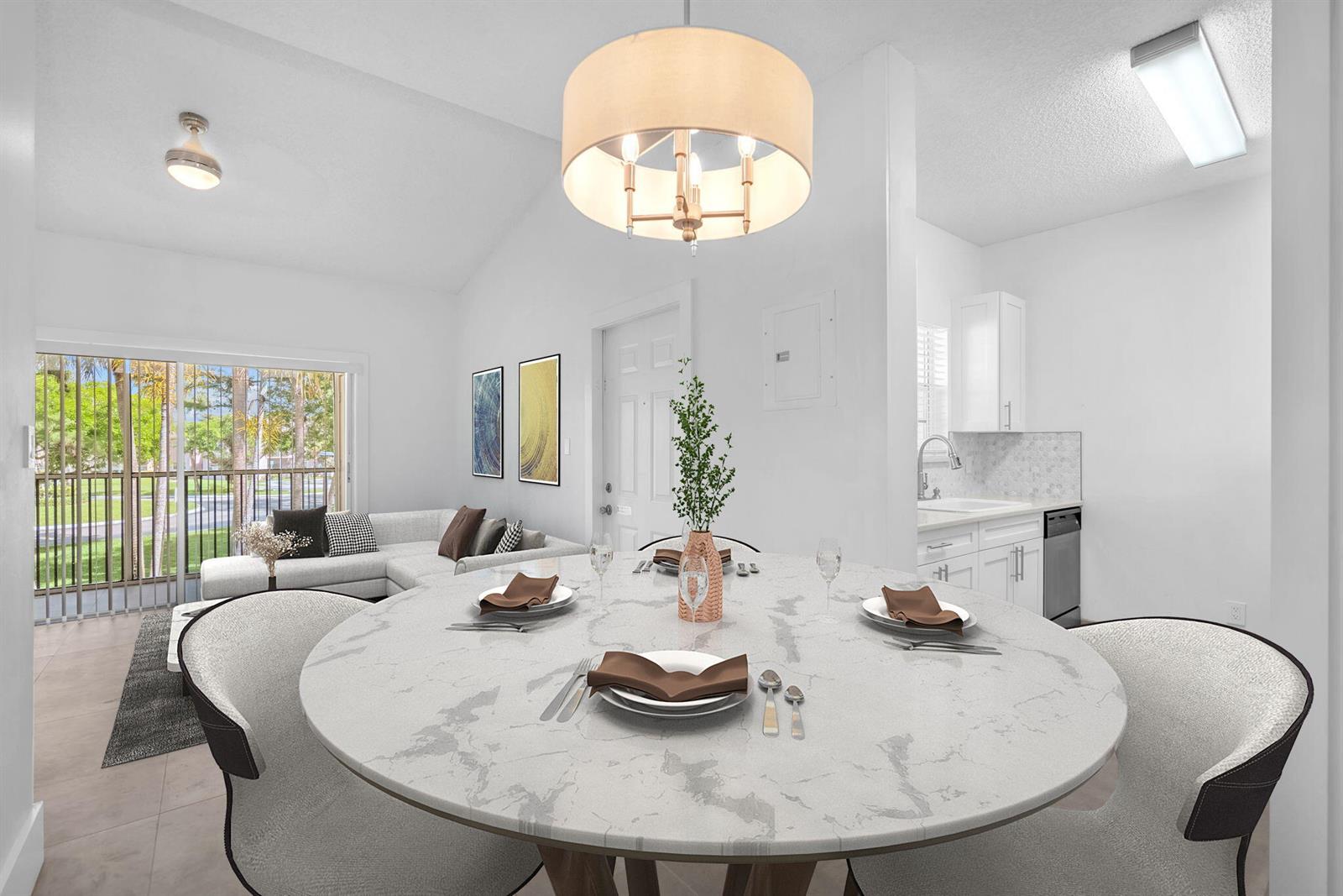 A dining area with a round marble table and chairs sits before a living room — 671 Cypress Lake Boulevard # L21, Deerfield Beach FL 33064, DEERFIELD BEACH, FL