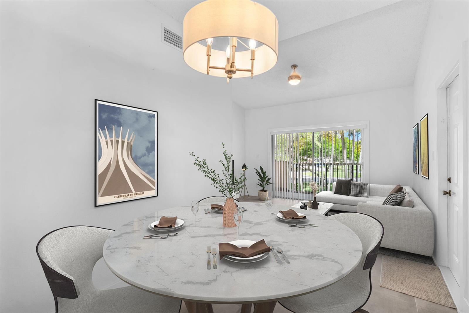 A dining area with a round marble table, modern chandelier, and a framed architectural print — 671 Cypress Lake Boulevard # L21, Deerfield Beach FL 33064, DEERFIELD BEACH, FL