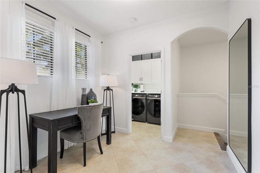 A home office space features a dark desk, a gray chair, and an adjacent laundry room — 8928 AZALEA SANDS LN UNIT 8928, DAVENPORT, FL