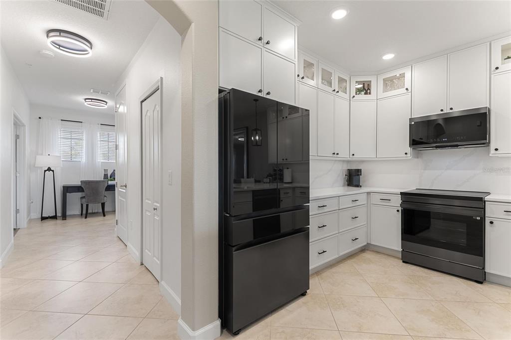 A kitchen with white cabinets, black appliances, and tile flooring leads to a small office — 8928 AZALEA SANDS LN UNIT 8928, DAVENPORT, FL