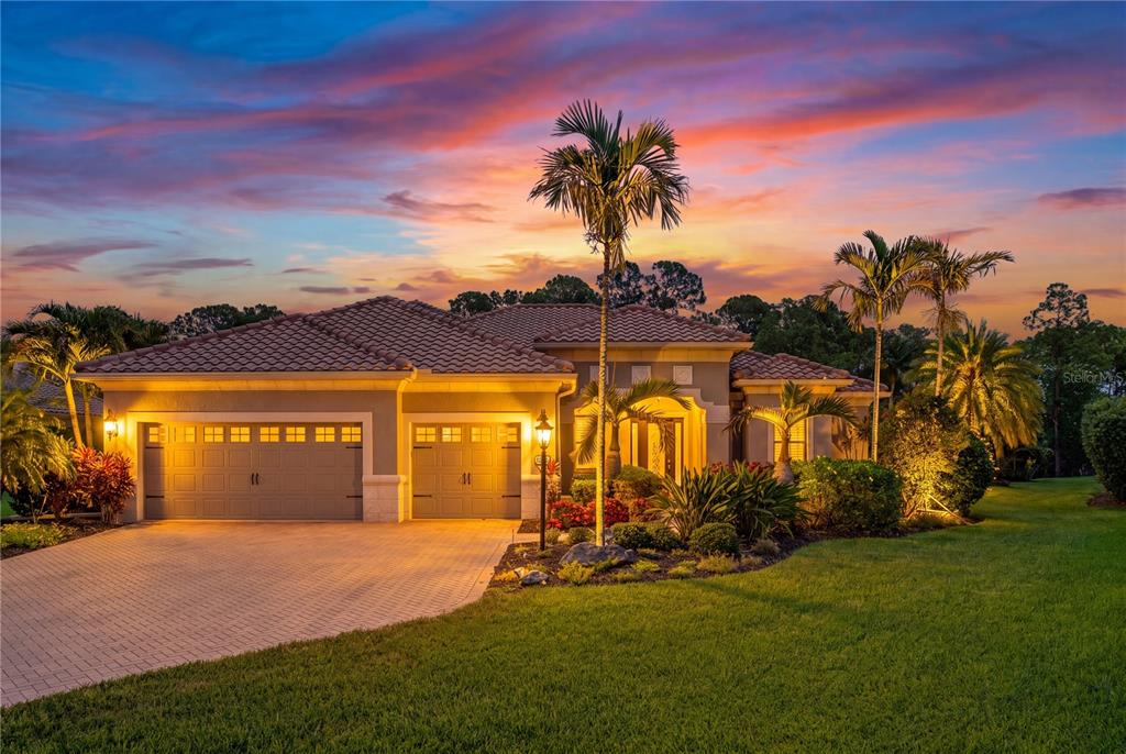 A single-story house with a two-car garage and palm trees at sunset — 8276 LARKSPUR CIRCLE, SARASOTA, FL