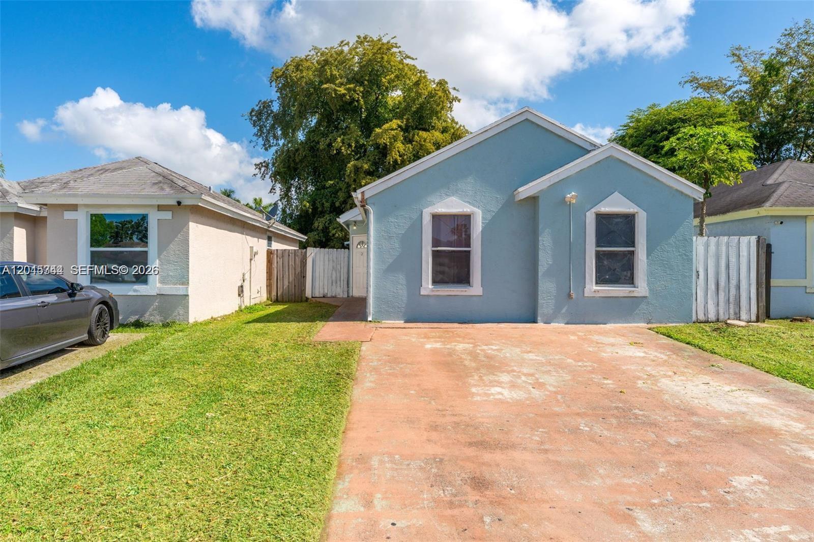 A light blue, single-story house features a concrete driveway and a small front lawn — 768 SW 9th St, Florida City FL 33034, FLORIDA CITY, FL