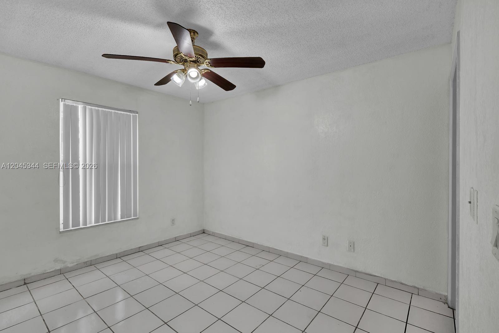 An empty room with white walls, white tile flooring, a ceiling fan, and a window — 768 SW 9th St, Florida City FL 33034, FLORIDA CITY, FL