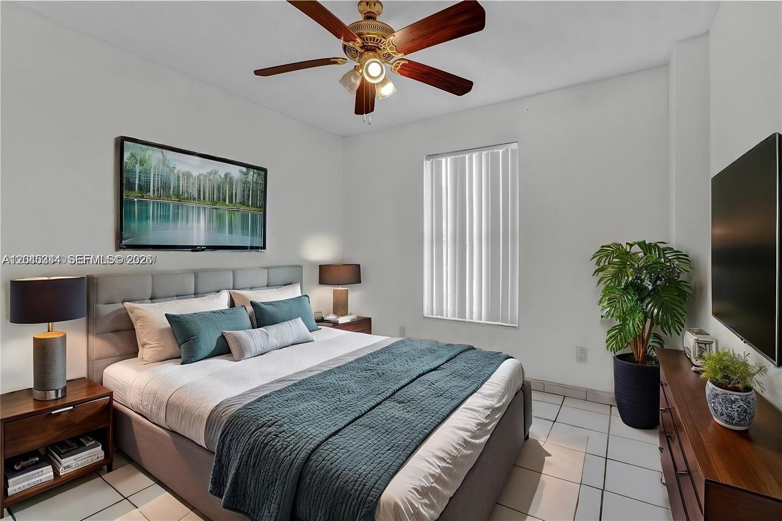 A bedroom features a gray upholstered bed, a ceiling fan, tiled floors, and a television — 768 SW 9th St, Florida City FL 33034, FLORIDA CITY, FL