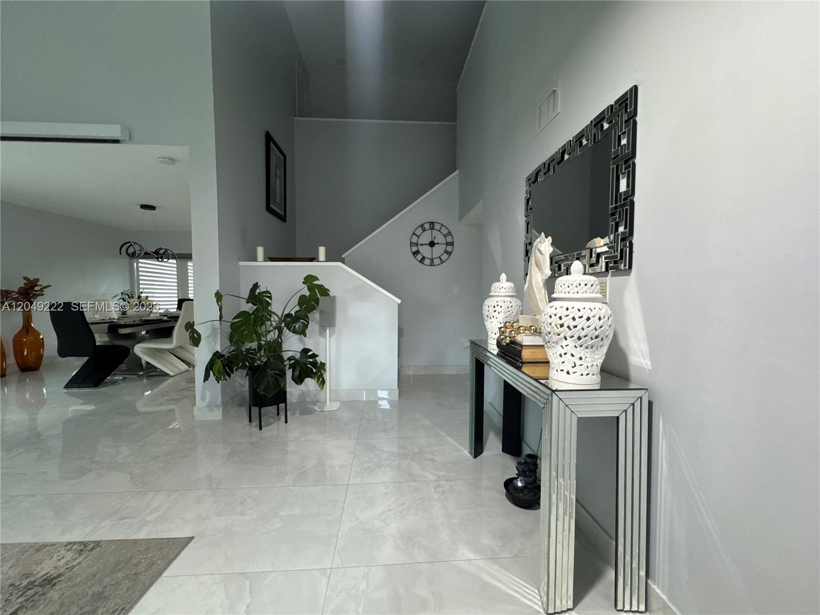 A bright entryway features white tile floors, a mirrored console table, and a staircase — 9368 SW 146th Pl # 0, Miami FL 33186, MIAMI, FL
