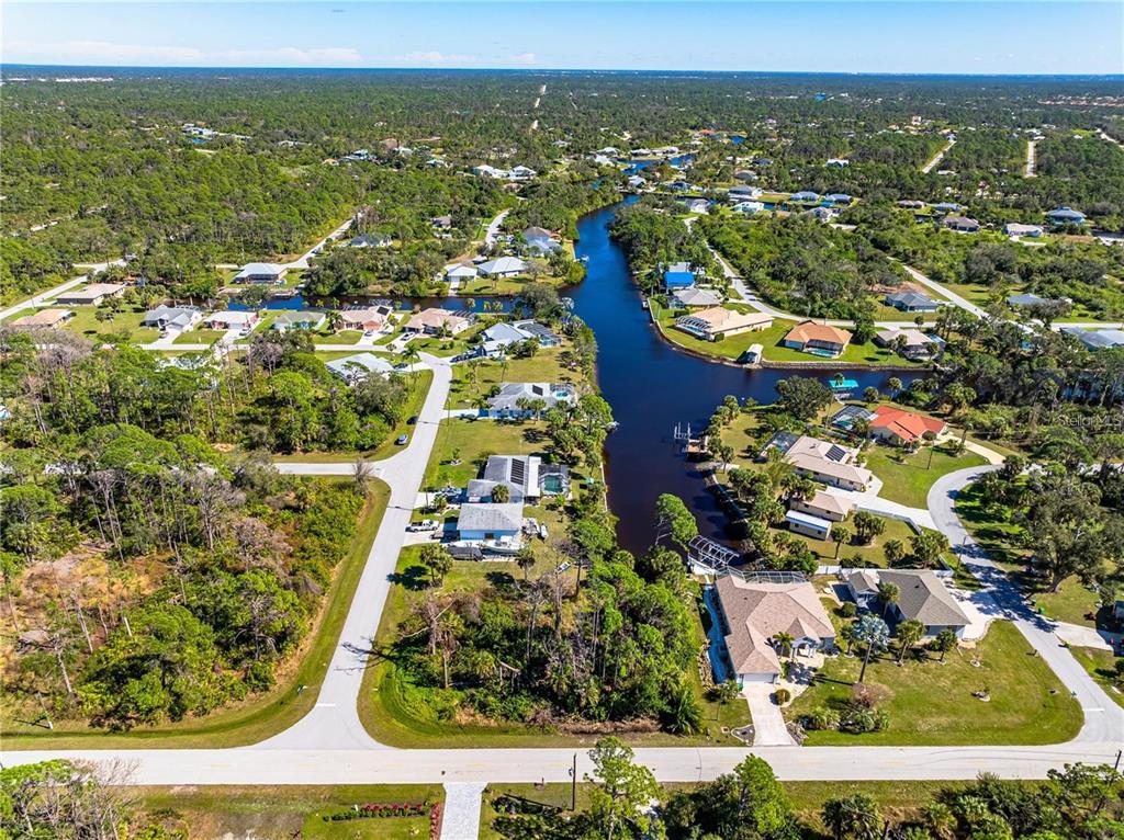 An aerial view shows houses situated along a canal surrounded by dense green vegetation — 1096 CAMPBELL STREET, PORT CHARLOTTE, FL