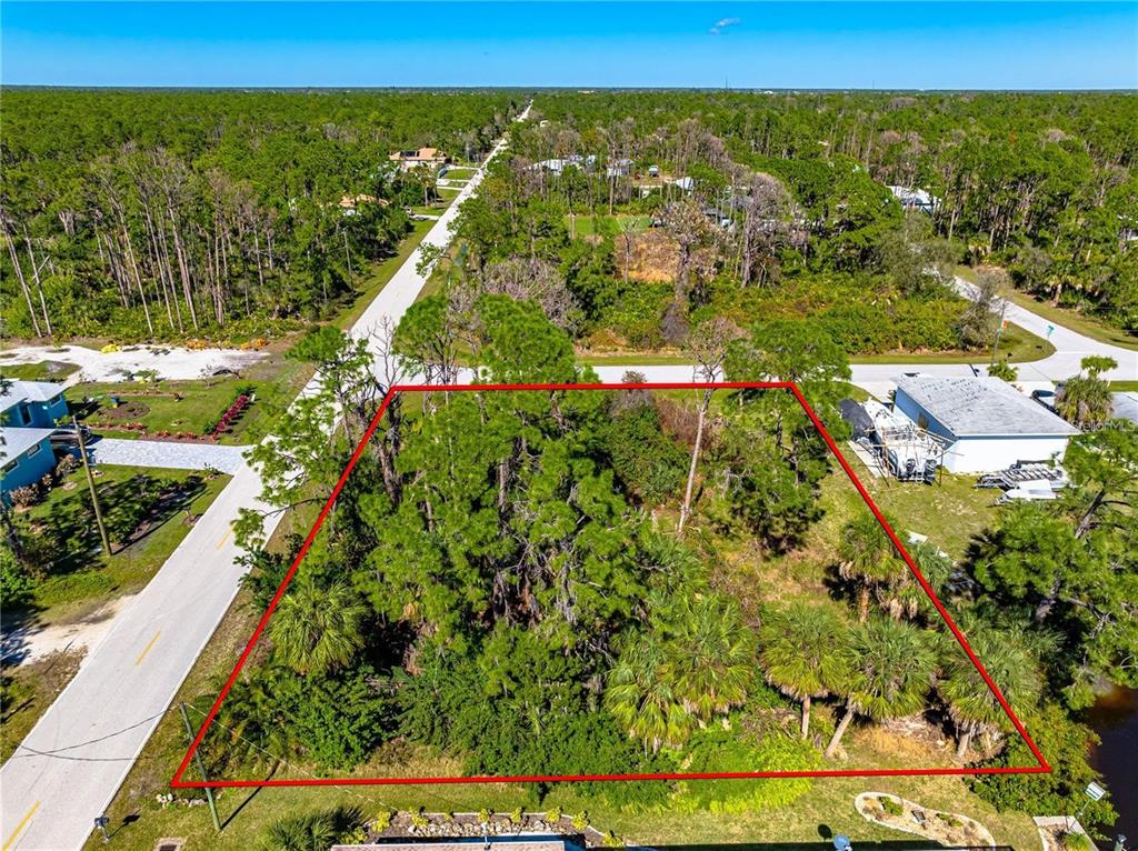 An aerial view shows a rectangular, wooded vacant lot outlined in red — 1096 CAMPBELL STREET, PORT CHARLOTTE, FL