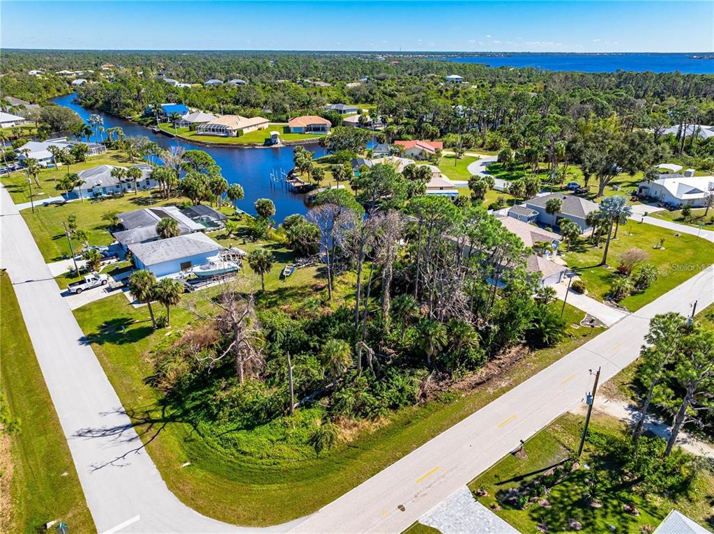 An aerial view shows a wooded vacant lot situated between two roads and a canal — 1096 CAMPBELL STREET, PORT CHARLOTTE, FL