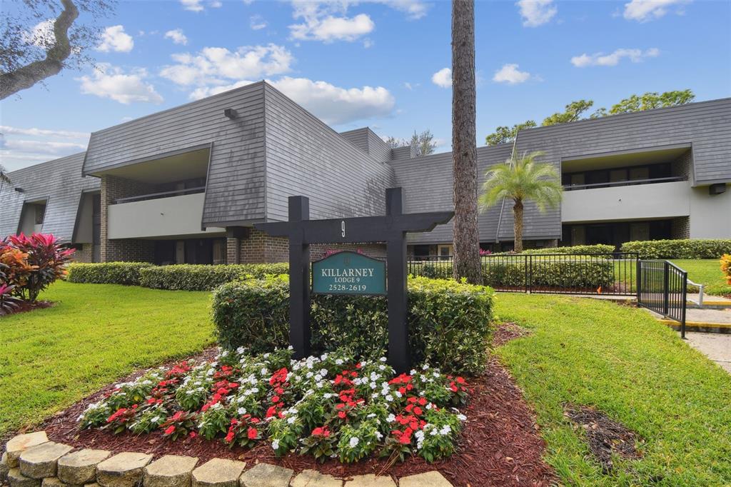 An entryway leads past a white kitchen into a living room with a balcony view — 36750 US HIGHWAY 19 N UNIT 09208, PALM HARBOR, FL
