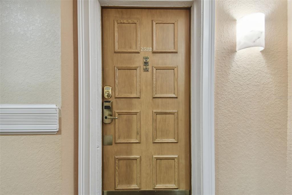 A small kitchen with white cabinets and appliances opens into a living room with balcony — 36750 US HIGHWAY 19 N UNIT 09208, PALM HARBOR, FL