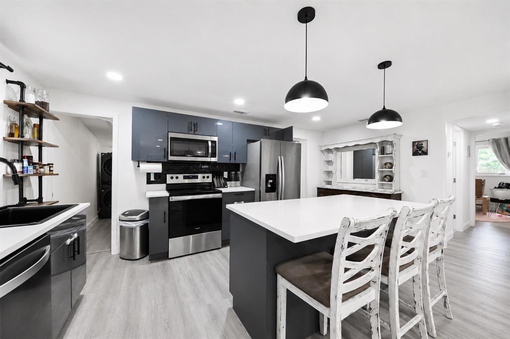 A modern kitchen features dark gray cabinets, a white island with seating, and stainless appliances — 4114 W OLIVE STREET, TAMPA, FL