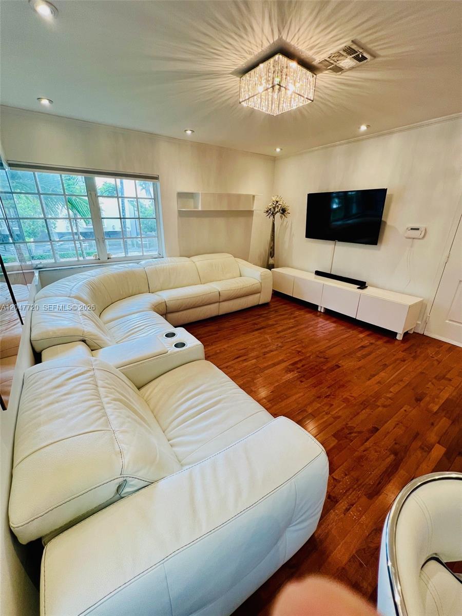 A living room features a white sectional sofa, hardwood floors, and a wall-mounted television — 600 Euclid Ave # 5B, Miami Beach FL 33139, MIAMI BEACH, FL