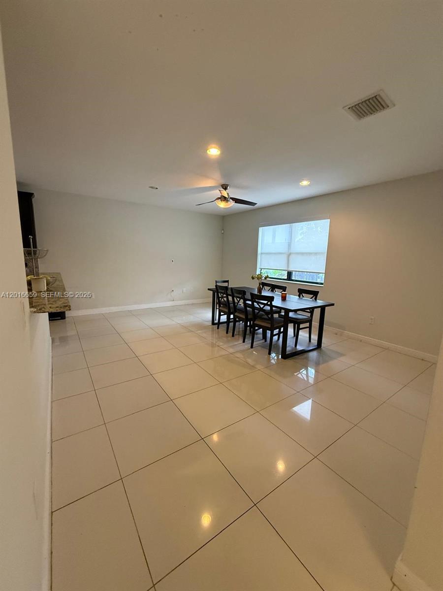 A dining area features light-colored tile flooring, a dark wood table with chairs, and recessed lighting — 9845 NW 86th Ter, Doral FL 33178, DORAL, FL