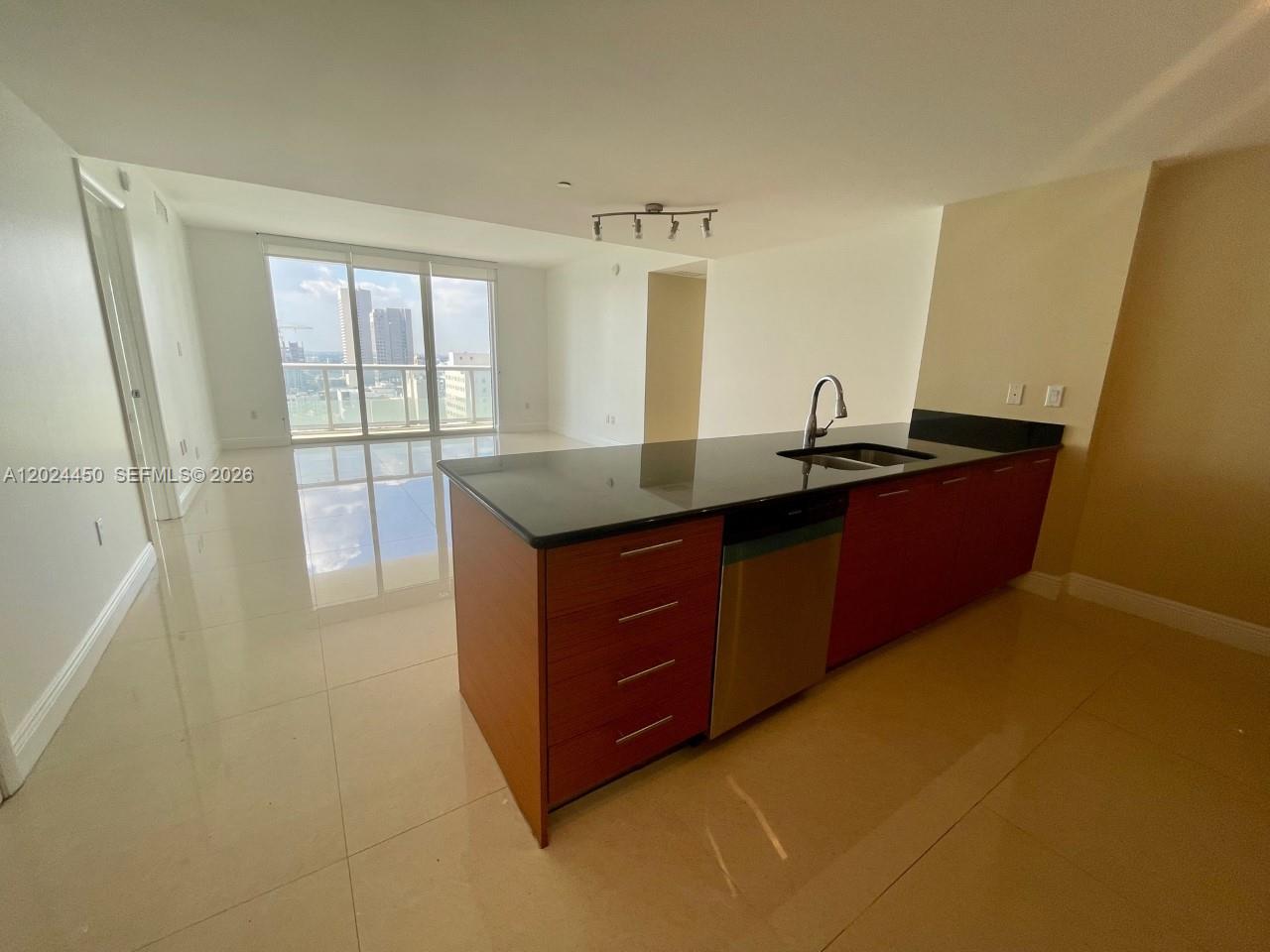 A kitchen island with dark countertops and wood cabinetry sits in an open-concept living space — 50 Biscayne Blvd # 2401, Miami FL 33132, MIAMI, FL