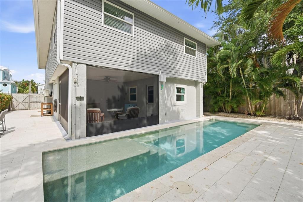 A gray two-story house with a screened-in patio overlooks a rectangular swimming pool — 2811 AVENUE C, HOLMES BEACH, FL