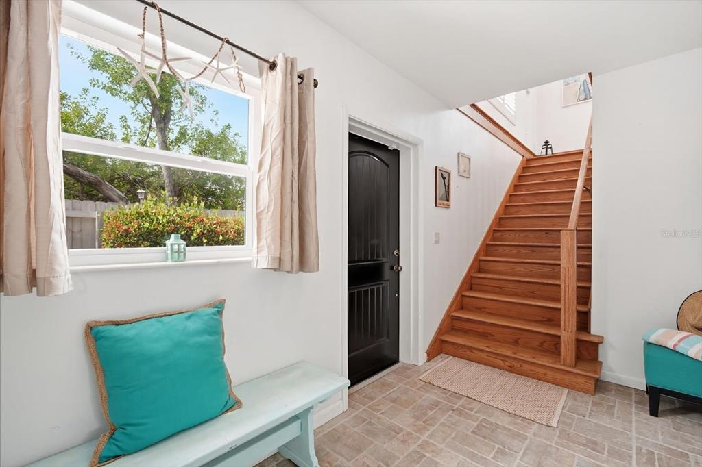 An entryway features a wooden staircase, a black door, a window, and a light blue bench — 2811 AVENUE C, HOLMES BEACH, FL