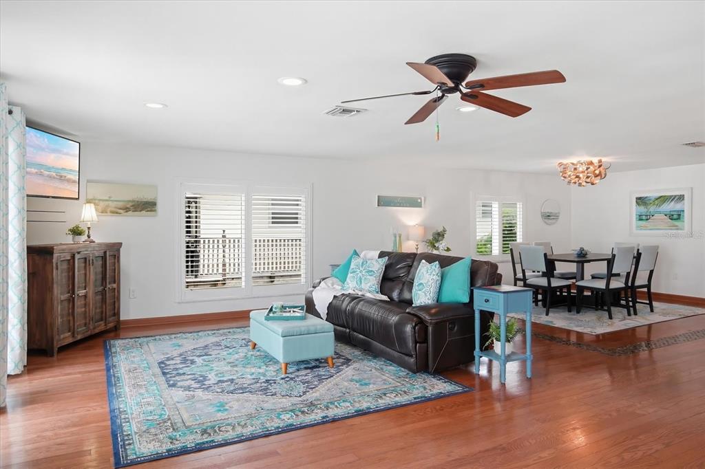 A living and dining area features hardwood floors, a dark leather sofa, and blue accents — 2811 AVENUE C, HOLMES BEACH, FL