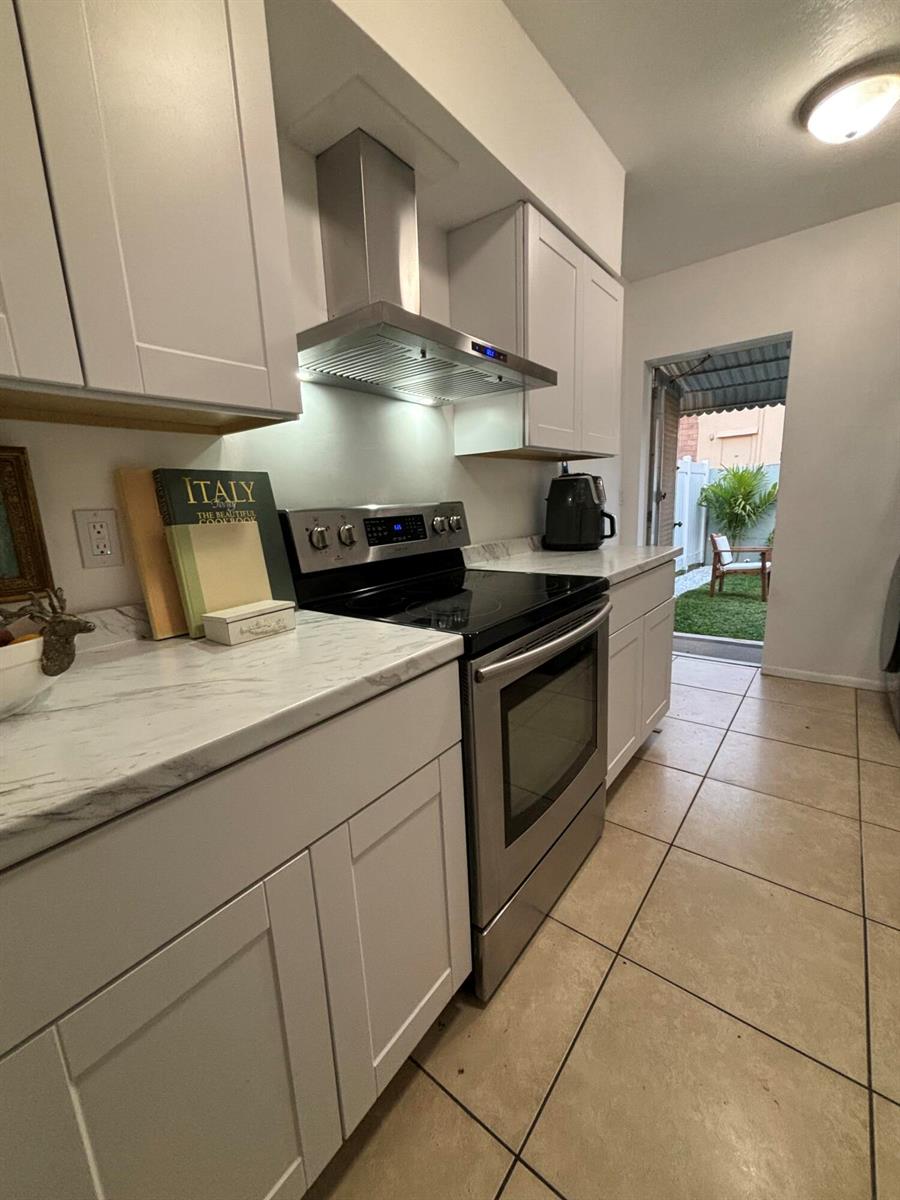 A kitchen features white shaker cabinets, marble-look countertops, stainless steel appliances, and a rear doorway — 262 SE 9th Avenue # 4, Deerfield Beach FL 33441, DEERFIELD BEACH, FL