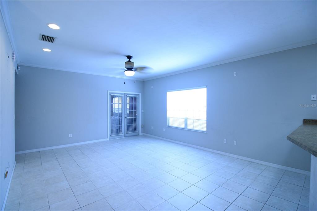 An empty room with light-colored tile flooring, a ceiling fan, and glass patio doors — 4742 NW 79TH ROAD, GAINESVILLE, FL