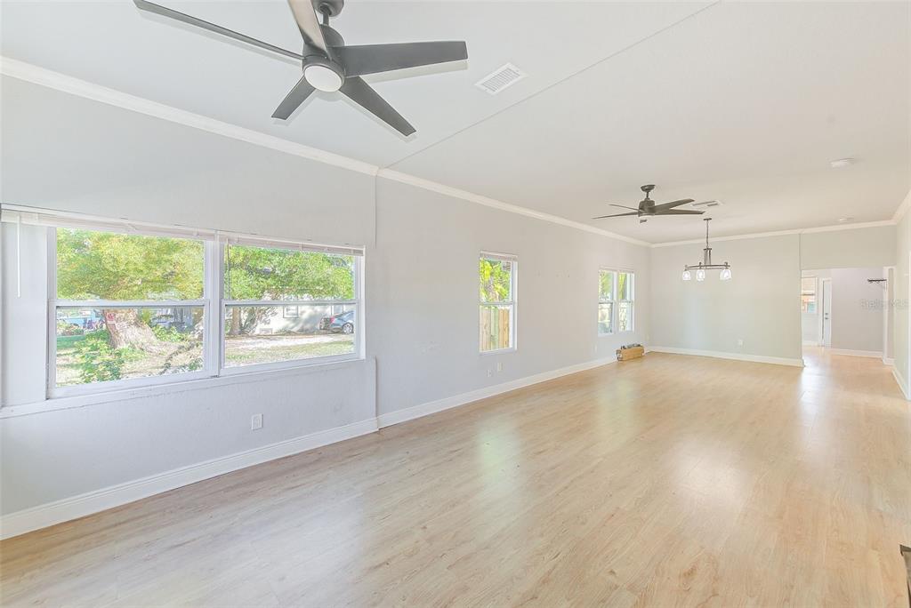 A spacious, light-filled living area features light wood-look flooring, two ceiling fans, and large windows — 2905 E 21ST AVENUE, TAMPA, FL