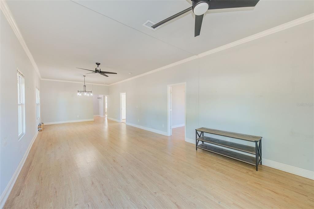 An empty room with light wood flooring, two ceiling fans, and a metal console table — 2905 E 21ST AVENUE, TAMPA, FL