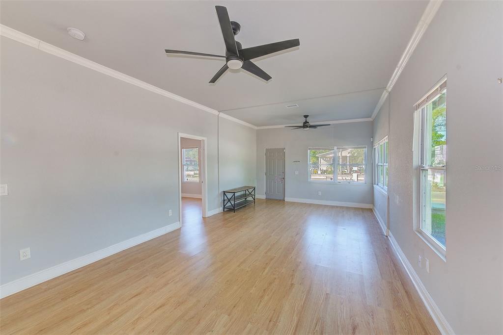 A bright living room features light wood flooring, gray walls, two ceiling fans, and windows — 2905 E 21ST AVENUE, TAMPA, FL