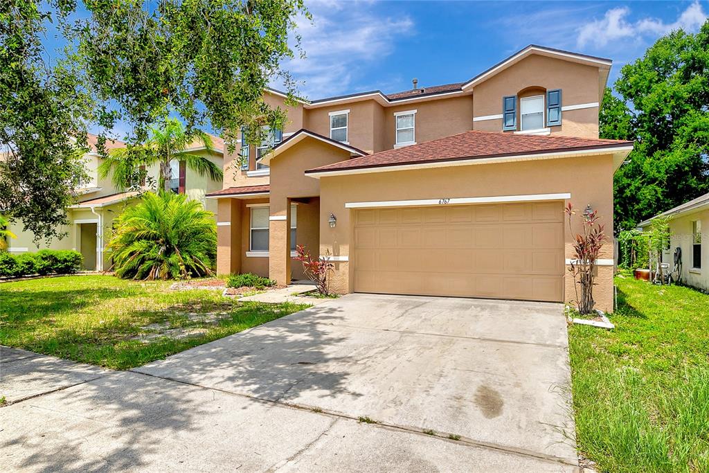 A two-story tan house with a two-car garage and a concrete driveway — 6767 WATERTON DRIVE, RIVERVIEW, FL