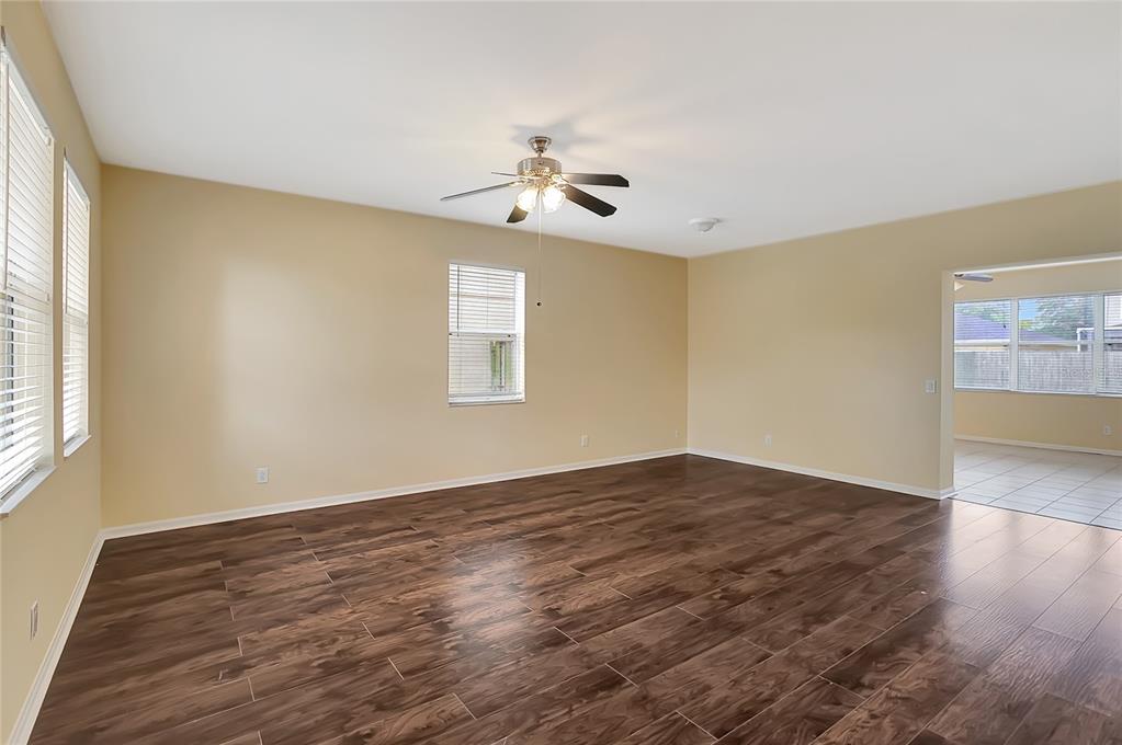 A living room with beige walls, dark wood-look tile flooring, and a ceiling fan — 6767 WATERTON DRIVE, RIVERVIEW, FL