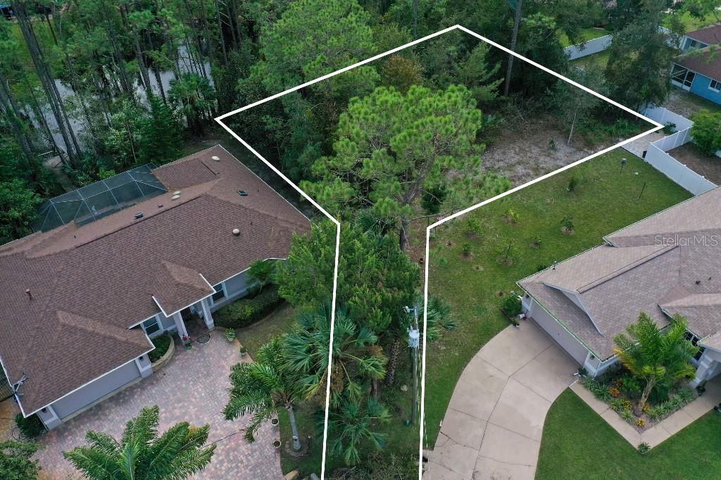 An aerial view shows a vacant, wooded residential lot outlined in white between two houses — 18 WATERMILL PLACE, PALM COAST, FL
