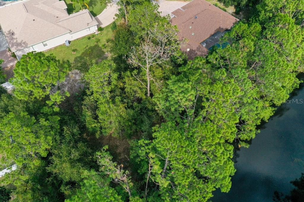 An aerial view shows a wooded lot situated between two houses and a body of water — 18 WATERMILL PLACE, PALM COAST, FL