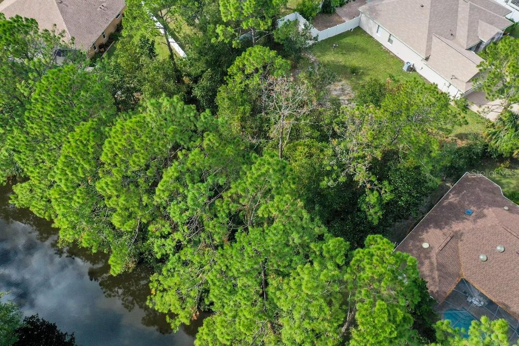 An aerial view shows a wooded lot situated between a canal and residential houses — 18 WATERMILL PLACE, PALM COAST, FL