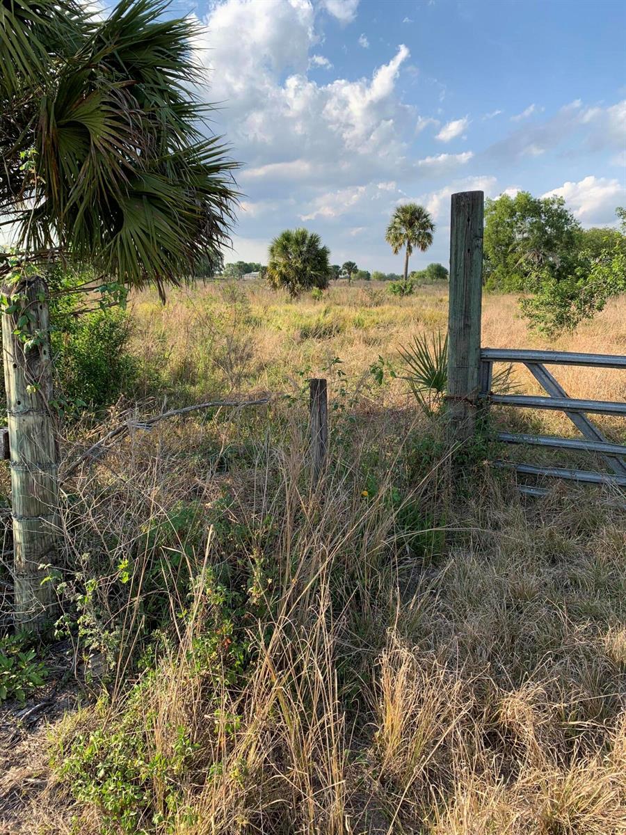 A metal gate and wooden fence posts stand at the edge of a grassy field — 20637 Simone Drive, Loxahatchee FL 33470, LOXAHATCHEE, FL