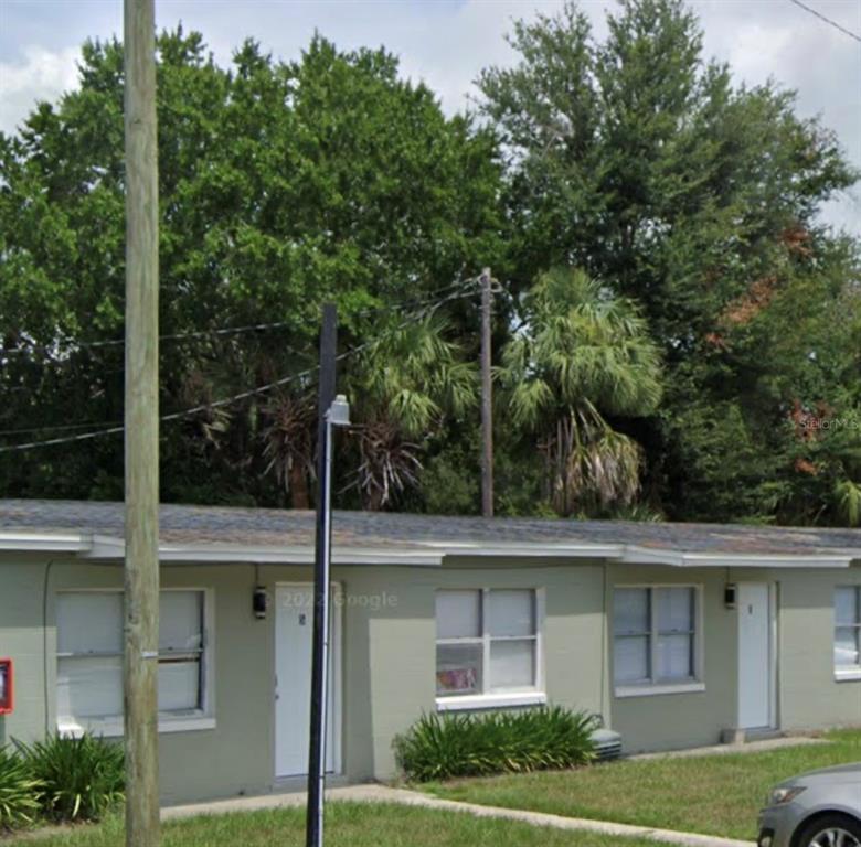A single-story, light green apartment building with white doors and windows under a cloudy sky — 3205 ORANGE CENTER BLVD, ORLANDO, FL