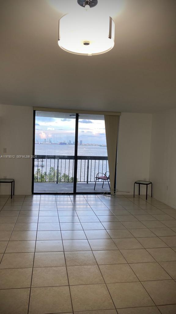 An empty room with tiled floors and a sliding glass door leading to a balcony — 2333 Brickell Ave # 1115, Miami FL 33129, MIAMI, FL