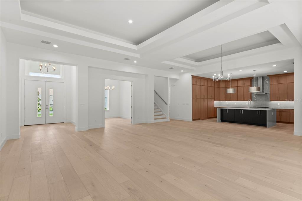 A spacious open-concept living area features light wood floors, a tray ceiling, and a kitchen — 1605 MANOR WOODS WAY, SANFORD, FL