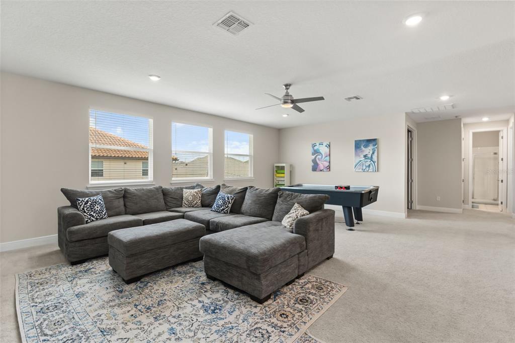 A spacious carpeted living room features a large gray sectional sofa and a pool table — 8373 LUDINGTON CIRCLE, ORLANDO, FL