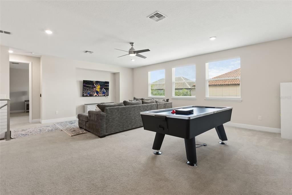 A carpeted living room features a gray sectional sofa, a television, and an air hockey table — 8373 LUDINGTON CIRCLE, ORLANDO, FL