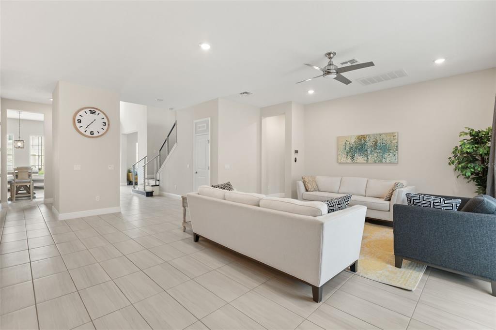 A living room features light tile flooring, a white sofa, and a staircase in the background — 8373 LUDINGTON CIRCLE, ORLANDO, FL