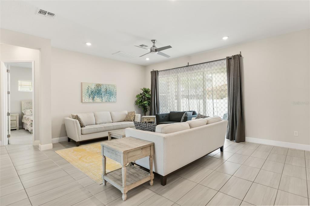 A living room features light tile floors, two sofas, a yellow rug, and large sliding doors — 8373 LUDINGTON CIRCLE, ORLANDO, FL