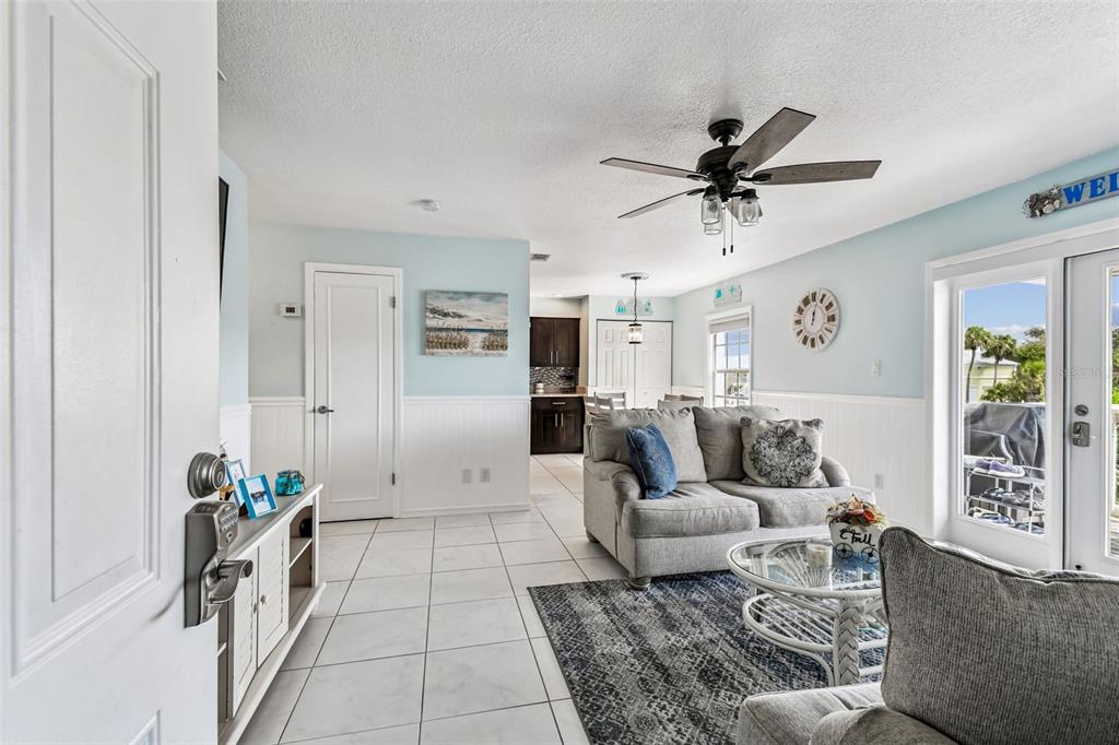 A living room with light blue walls, white wainscoting, tile floors, and a ceiling fan — 5116 BEACH DRIVE SE UNIT D, ST PETERSBURG, FL
