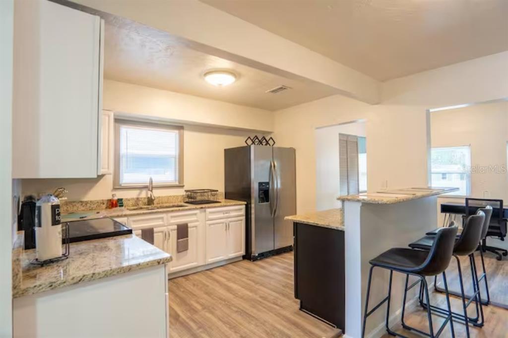 A kitchen features white cabinets, granite countertops, stainless steel appliances, and a breakfast bar — 2008 PAGE AVENUE, ORLANDO, FL