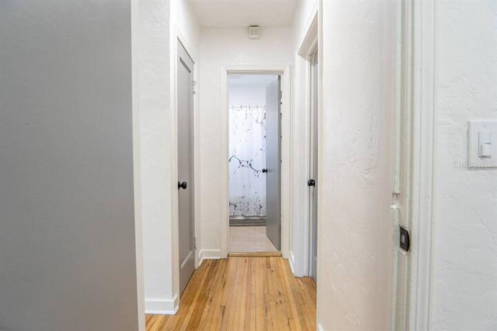 A hallway with hardwood floors leads to a bathroom with a shower curtain — 2008 PAGE AVENUE, ORLANDO, FL