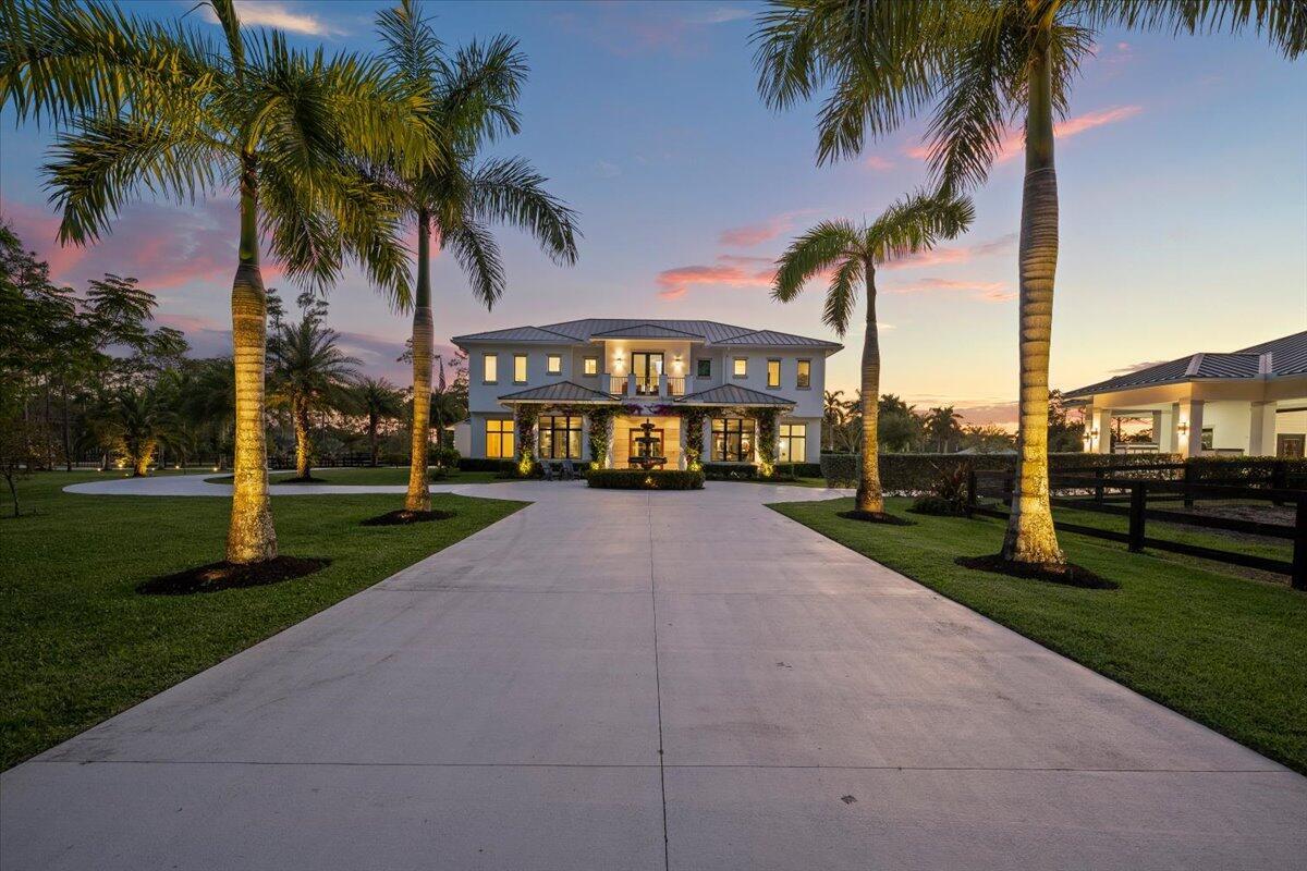 A two-story house with a concrete driveway and palm trees at sunset — 6209 Homeland Road, Lake Worth FL 33449, LAKE WORTH, FL