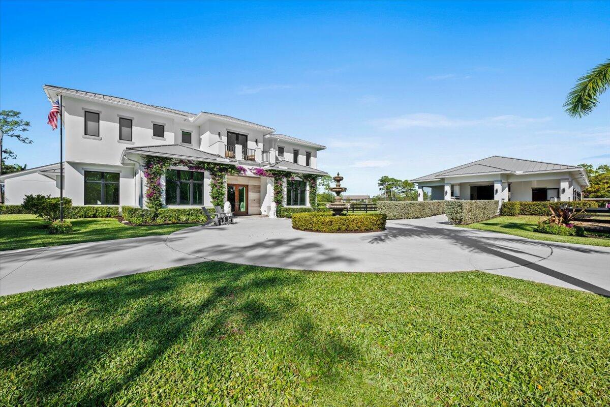 A two-story white house with a circular driveway and a fountain in the front yard — 6209 Homeland Road, Lake Worth FL 33449, LAKE WORTH, FL