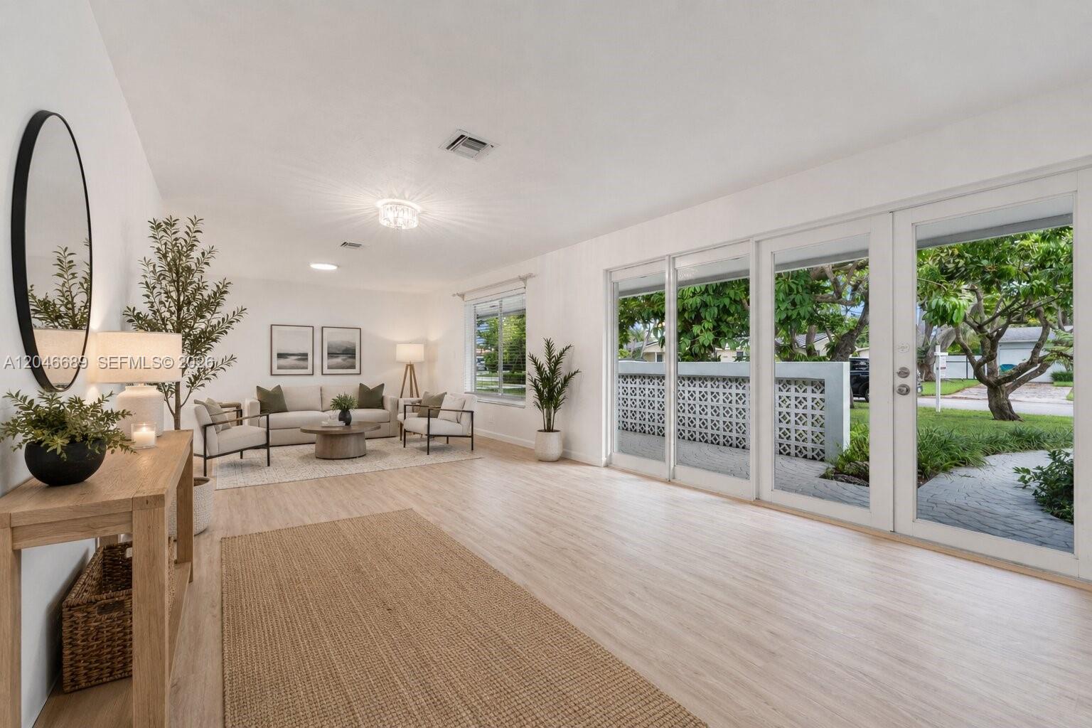 A bright living room features light wood flooring, a neutral seating area, and glass sliding doors — 7982 SW 89th St # 7982, Miami FL 33156, MIAMI, FL