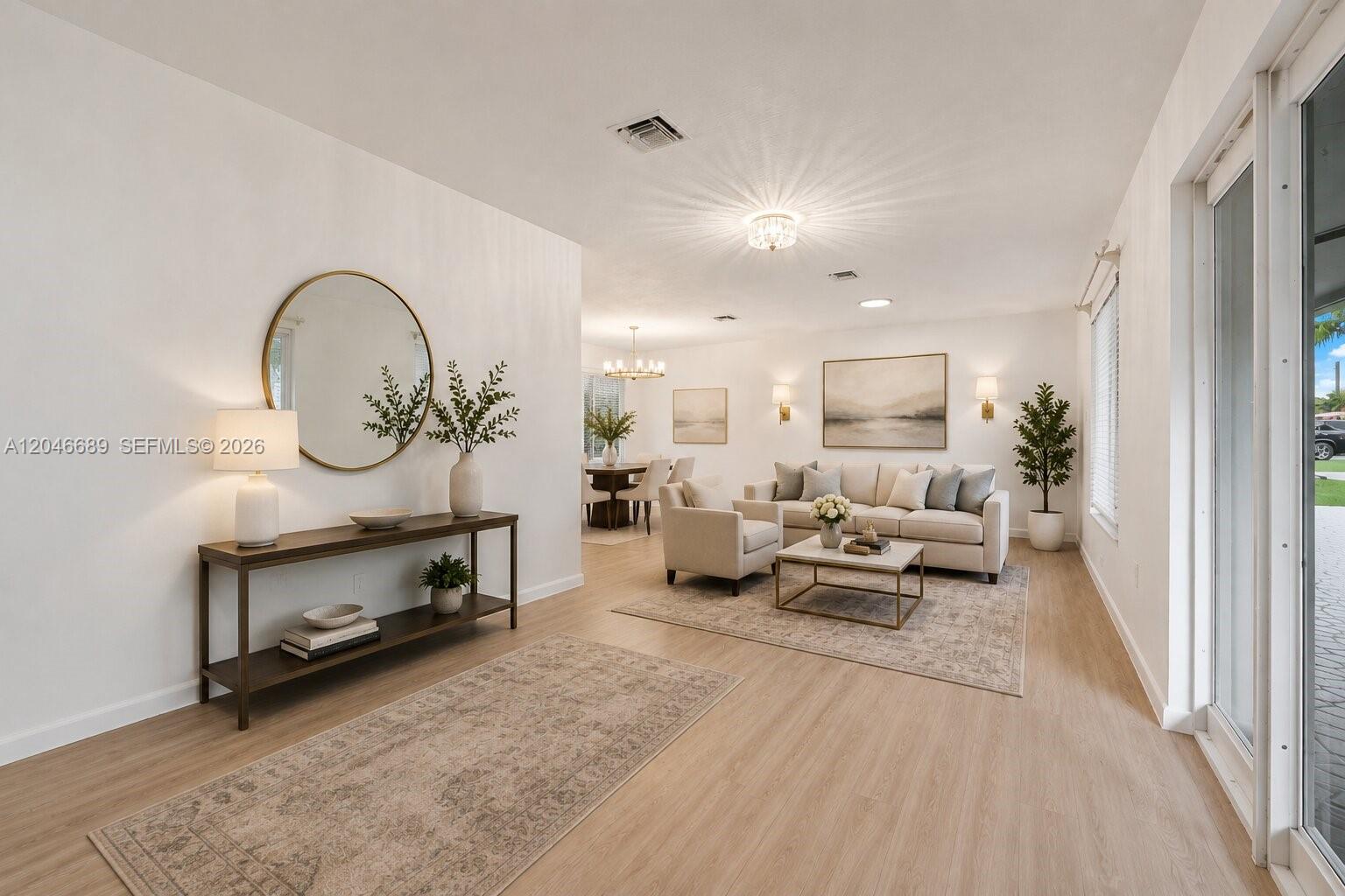 A bright living room features light wood flooring, a neutral sofa, and a round mirror — 7982 SW 89th St # 7982, Miami FL 33156, MIAMI, FL